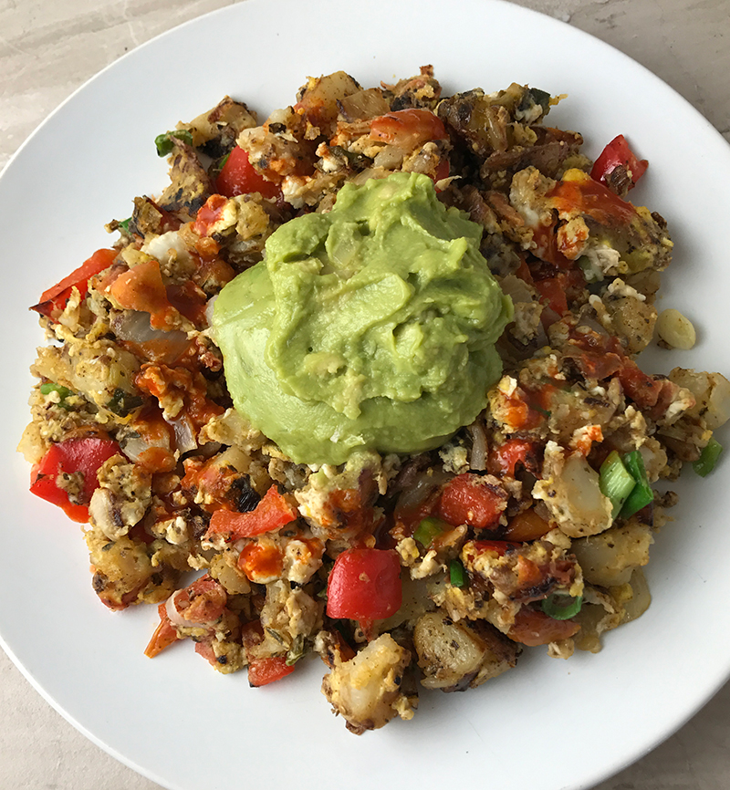 Whole30 Potato and Vegetable Egg Scramble Topped With Avocado and Tapatio
