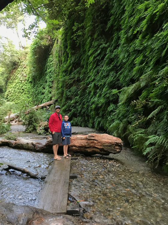 Brian and Carter Standing on a plank across the creek in fern canyon
