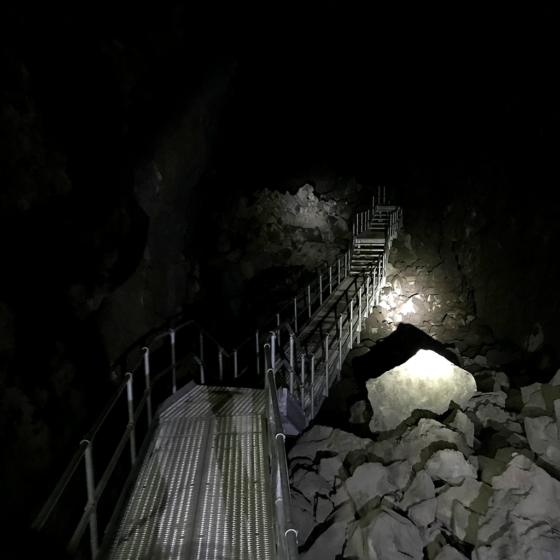 Steel Walkway and Stairs Descending Into The Pitch Black Lava River Cave